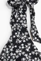 Traje de baño enterizo negro con estampado floral blanco, escote en V y breteles con moños.