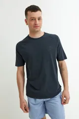 Remera de manga corta color azul oscuro o negro deslavado, con cuello redondo y corte raglán. Presenta un pequeño estampado en el pecho con texto en relieve.