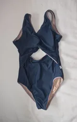 Traje de baño entero azul con forro color piel, con escote cruzado y abertura en el abdomen.