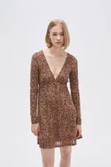 Vestido corto color beige con estampado animal print, escote en V, mangas largas y falda evasé con volados. Ajuste con lazo en la cintura.