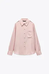 Camisa color rosa de manga larga, con cuello solapa, trabillas en los hombros, bolsillo delantero y cierre frontal con botones.