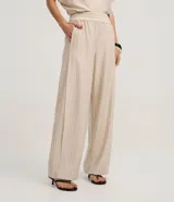 Pantalón de mujer de tiro alto, corte wide leg, color beige con finas rayas verticales en tono oscuro. Presenta cintura elástica fruncida y caída fluida.