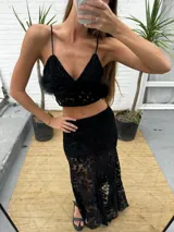 Top de encaje negro con escote en V, tirantes finos, detalles de terciopelo y plumas desmontables en el bajo.