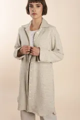 Camisa larga color crema con rayas verticales finas en gris, con botones dorados y bolsillo plaque en la delantera.