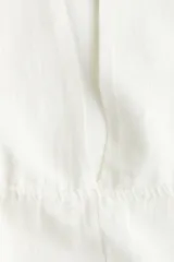 Túnica playera blanca de manga corta con escote en V y cordones ajustables en la cintura.