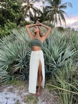 Falda larga cruzada color crudo, confeccionada en tejido de punto con lurex y viscosa.