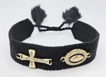 Pulsera tejida color gris con cierre ajustable y dijes dorados: una cruz con strass y un dije ovalado con la imagen de la Virgen María rodeada de strass.