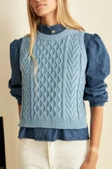 Chaleco celeste de punto con diseño trenzado, cuello redondo y corte recto.