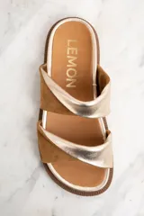 Sandalias bajas con base dorada y dos tiras anchas cruzadas en cuero color marrón y dorado.