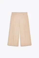Bermudas color beige de tiro alto con trabillas en la cintura, pinzas en el delantero y cierre lateral con cremallera oculta.