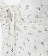 Vestido midi de punto acanalado color crema con estampado floral, breteles finos y escote fruncido con lazo.