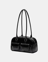 Bolso tipo bowling de charol negro con doble asa de hombro y cierre superior con cremallera. Tiene dos bolsillos frontales de parche.
