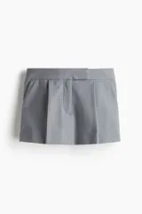Short pollera corto de sastre color gris, con pinzas frontales, pretina ancha con cierre y corchetes, y bolsillos al bies.