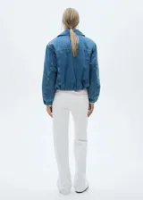 Campera de jean azul con cuello clásico, cierre frontal con cremallera, bolsillos laterales y mangas largas con puños elásticos.