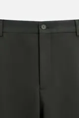 Pantalón relaxed fit color verde oscuro, con pliegues en la parte delantera, bolsillos laterales y traseros de ojal. Cierre frontal con cremallera y botón.