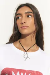 Collar con cordón negro y dije plateado en forma de sol con puntas.