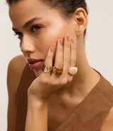 Set de tres anillos con diferentes diseños: uno dorado con textura, uno marrón con forma cuadrada y uno blanco marmolado.