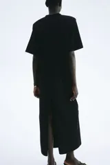 Vestido largo (tobillero) negro de corte recto y holgado, tipo remerón, con cuello redondo y mangas cortas.