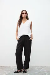 Pantalón negro de lino, de corte ancho y tiro alto, con pinzas en la cintura y bolsillos laterales.