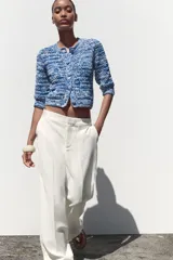 Chaqueta de punto azul y blanco con cuello redondo y manga francesa. Tiene bolsillos delanteros de plastrón y cierre frontal con botones a tono.