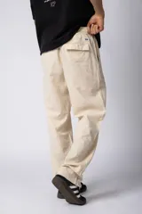 Pantalón de lino y algodón color beige claro, de calce suelto y tiro medio/alto con cintura elastizada y cordón regulable. Posee bolsillos laterales y un bolsillo trasero con tapa.