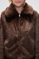 Chaqueta corta negra de piel sintética con cuello clásico, cierre frontal con cremallera y mangas largas.