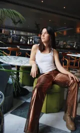 Pantalón de cuero ovino color cobre metalizado, de tiro alto y corte recto con abertura en el bajo.