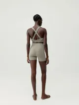 Short deportivo color arena, de tiro alto, confeccionado en tejido técnico con costuras termoselladas y cinta reflectante decorativa.
