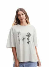 Remera blanca de corte amplio con estampado de tres flores en negro.