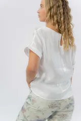 Blusa gris lavanda metálico de corte recto y fluido, con mangas cortas con vuelta, escote redondo y abertura en la espalda.