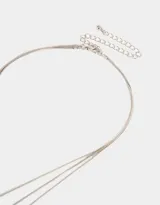 Collar dorado multicadena con tres cadenas de diferentes largos, cada una con un dije de corazón.