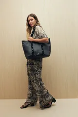 Bolso shopper de símil cuero color beige, con asas largas decoradas con tachas metálicas.