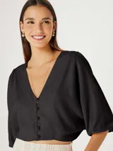 Blusa beige con escote en V, mangas 3/4 abullonadas y cierre frontal con botones.