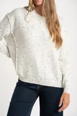 Sweater de punto color gris melange con efecto tweed o salpicado en negro, de calce oversize y cuello redondo.