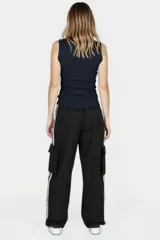 Pantalón negro de corte ancho con cintura elastizada y cordón ajustable. Presenta una franja vertical blanca a lo largo de la pierna y un bolsillo tipo cargo en el muslo.