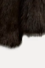 Abrigo corto marrón de pelo sintético, con cuello solapa, manga larga, bolsillos delanteros, forro interior y cierre frontal con botón.