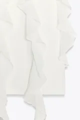 Camiseta blanca de algodón con cuello redondo, manga corta y volantes de gasa en el frente.