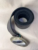 Cinturón de cuero negro con hebilla intercambiable en diseño metálico.