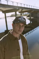 Gorra marrón de cinco paneles con bordado frontal con la inscripción "TT Archive Club Creative Dept. Established 1990".