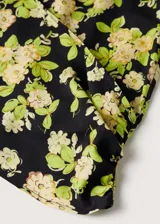 Blusa crop de tejido satinado con estampado floral, cuello cruzado, mangas largas con puños elásticos y elástico en el bajo.