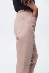 Pantalón de jean gris oscuro, de corte mom fit, tiro alto y largo tobillero. Cuenta con cinco bolsillos, cierre frontal con cremallera y botón.