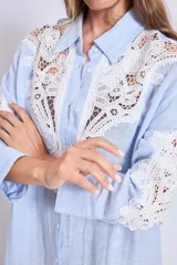 Vestido camisero celeste de lino con apliques de encaje blanco en cuello, mangas y frente.