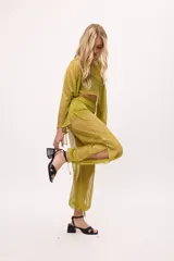 Pantalón negro traslúcido con corte ancho y ajuste en los tobillos.