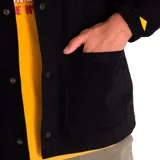 Chaqueta negra de twill de algodón con cierre frontal a presión, bolsillos superiores en el pecho y en la parte inferior, puños elásticos, forro con logo de Caterpillar y bolsillo interior en el pecho.