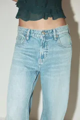 Pantalón de jean azul oscuro, de corte wide leg y tiro medio, con cinco bolsillos y cierre frontal con cremallera y botón metálico.