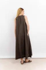 Vestido largo confeccionado en lino de color beige, con escote en V, diseño sin mangas y silueta holgada de caída fluida.