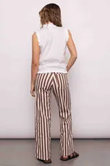 Blusa blanca sin mangas con cuello mao y volados en hombros y ruedo. Cierre frontal con botones.