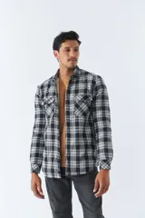 Sobrecamisa de algodón para hombre con interior de corderito, estampado a cuadros en tonos negro, blanco y azul. Tiene cierre de botones, bolsillos tipo cartera y logo en goma. El modelo usa talle M.