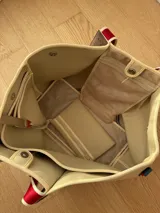 Bolso negro tipo tote de neopreno con bolsillo interno de red, sobre haciendo juego y gancho para sujetarlo.