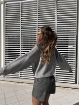 Buzo gris de corte holgado con cuello polo y cierre parcial con botones. De mangas largas y tejido de punto. 